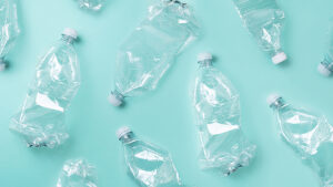 绿松石背景上透明塑料空瓶的照片。